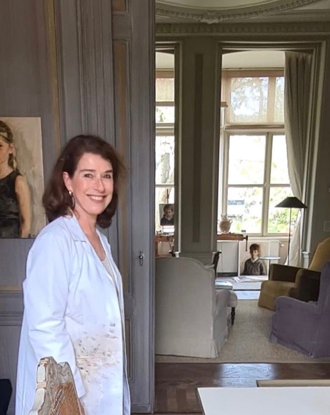 Een vrouw in een witte jas staat in een woonkamer.