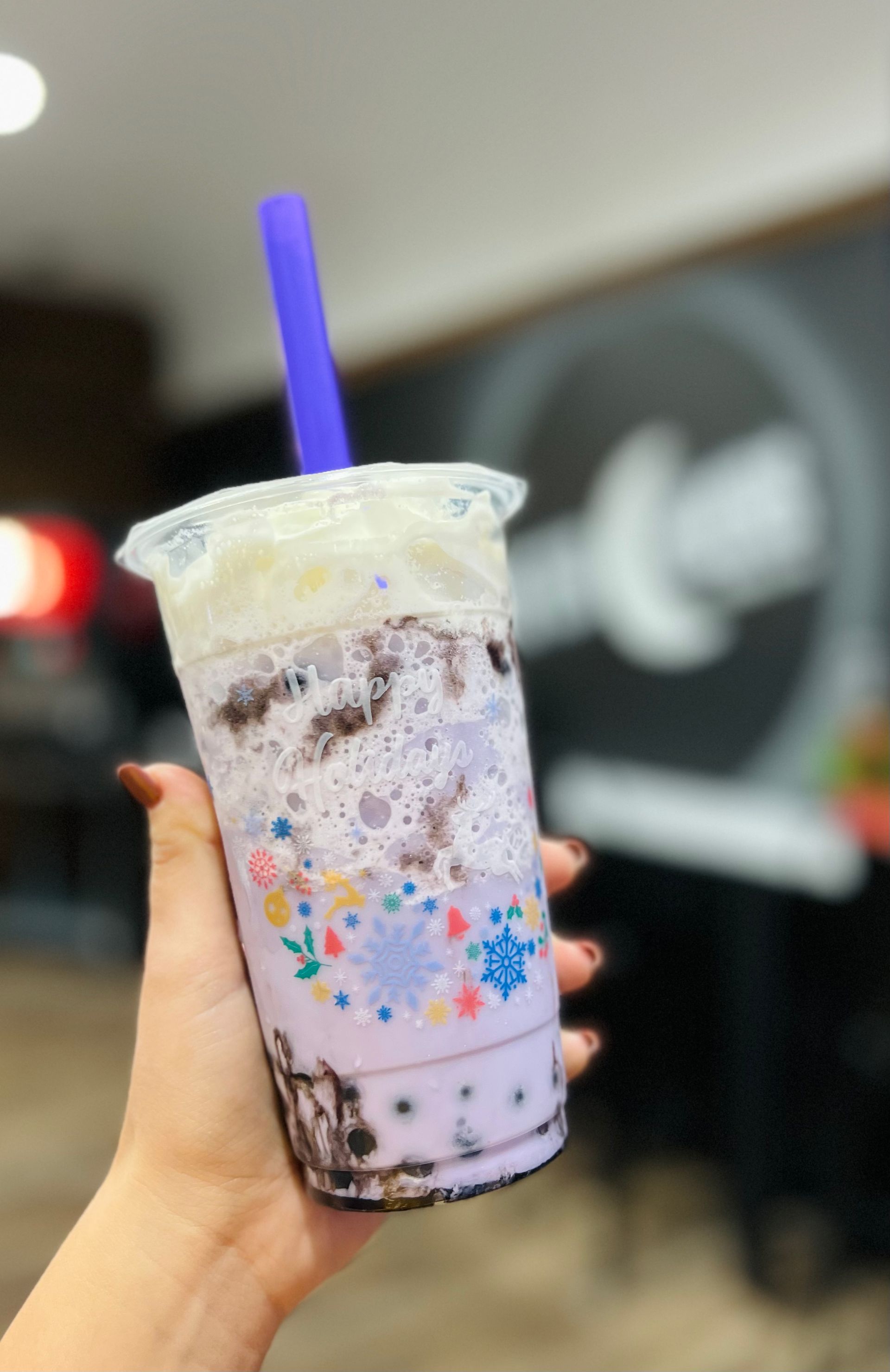 a person is holding a purple drink with a purple straw .