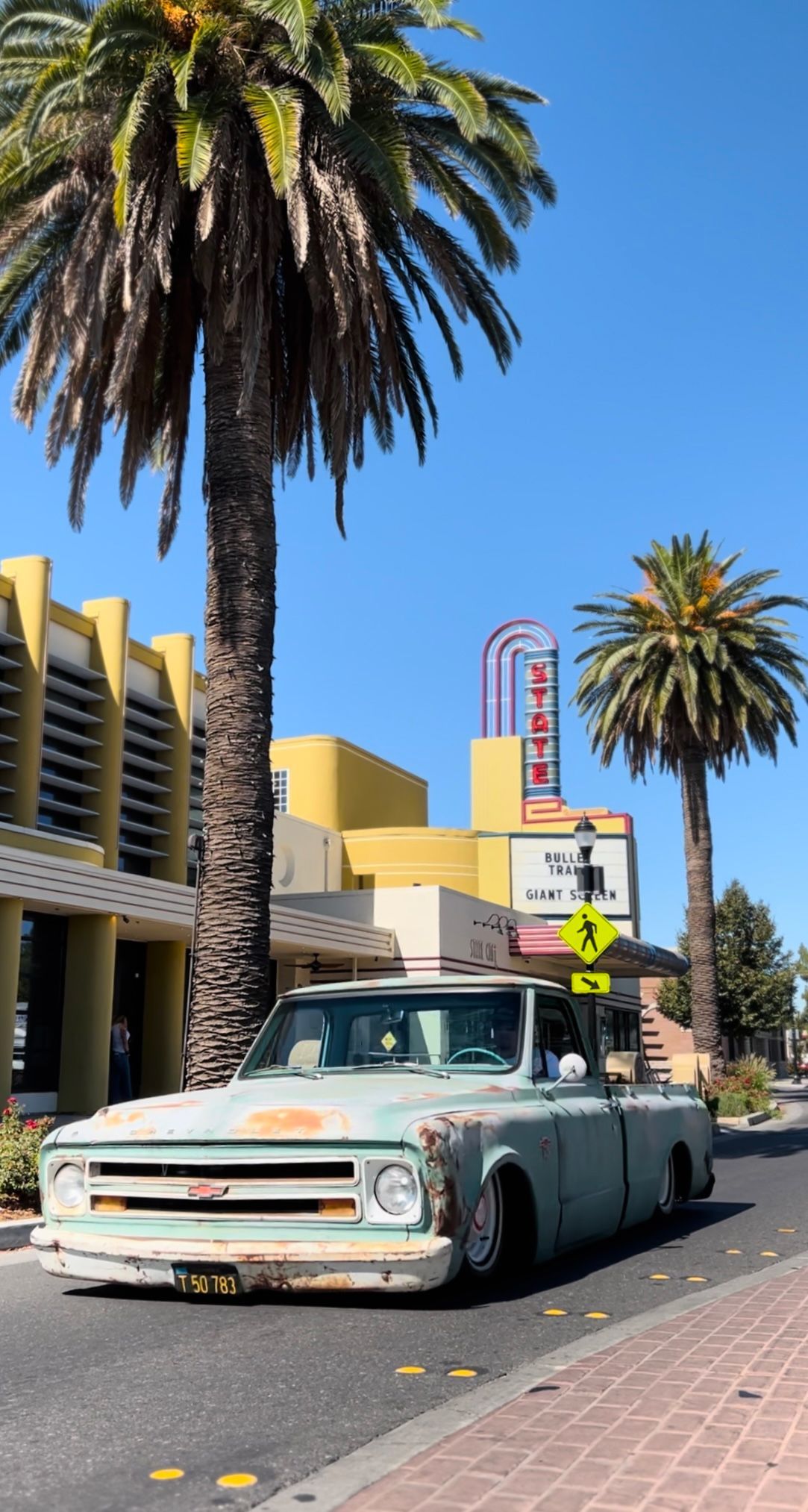 a pickup truck is parked on the side of the road next to palm trees .