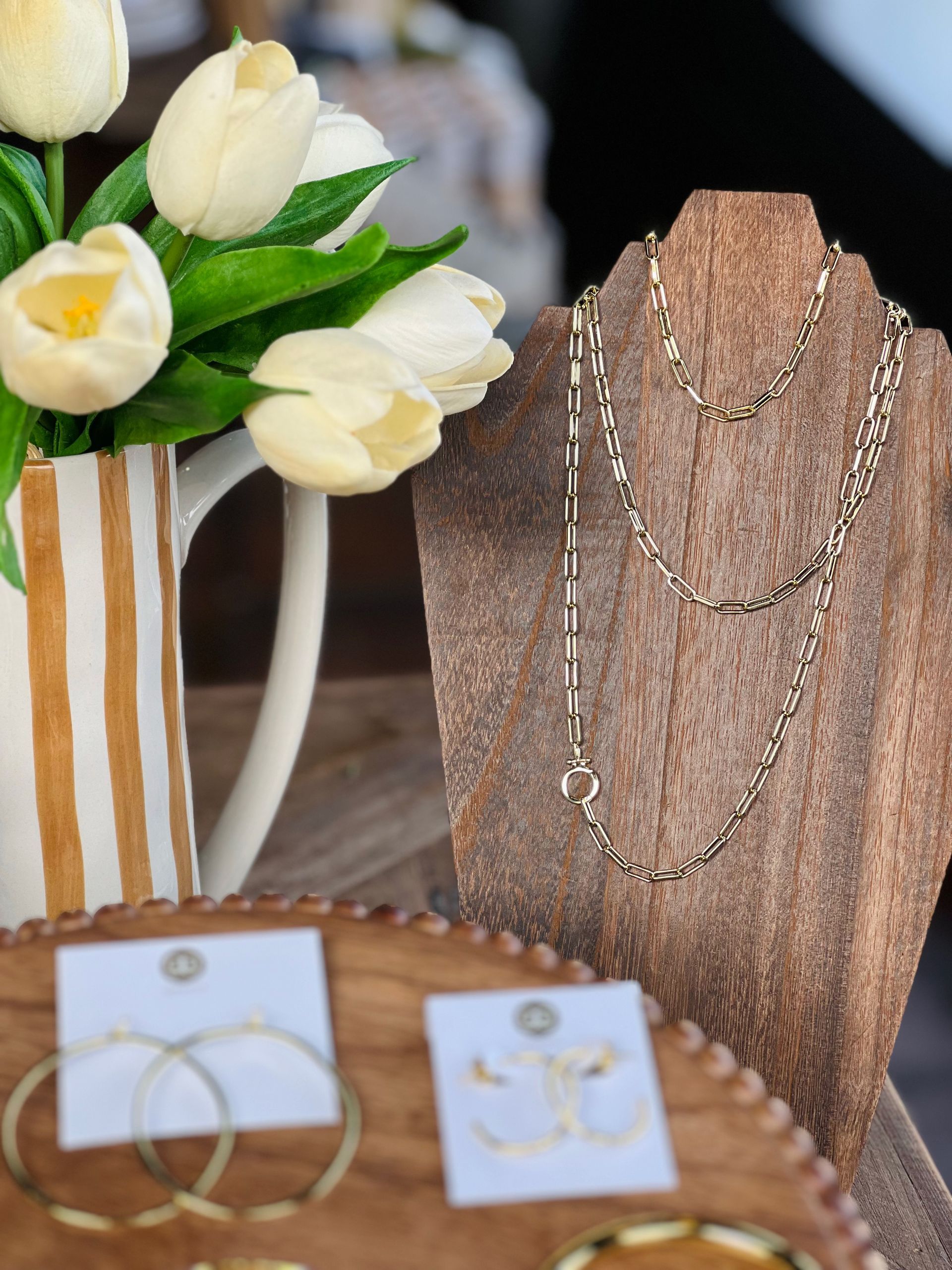 a necklace and earrings are on display on a table next to a vase of flowers .