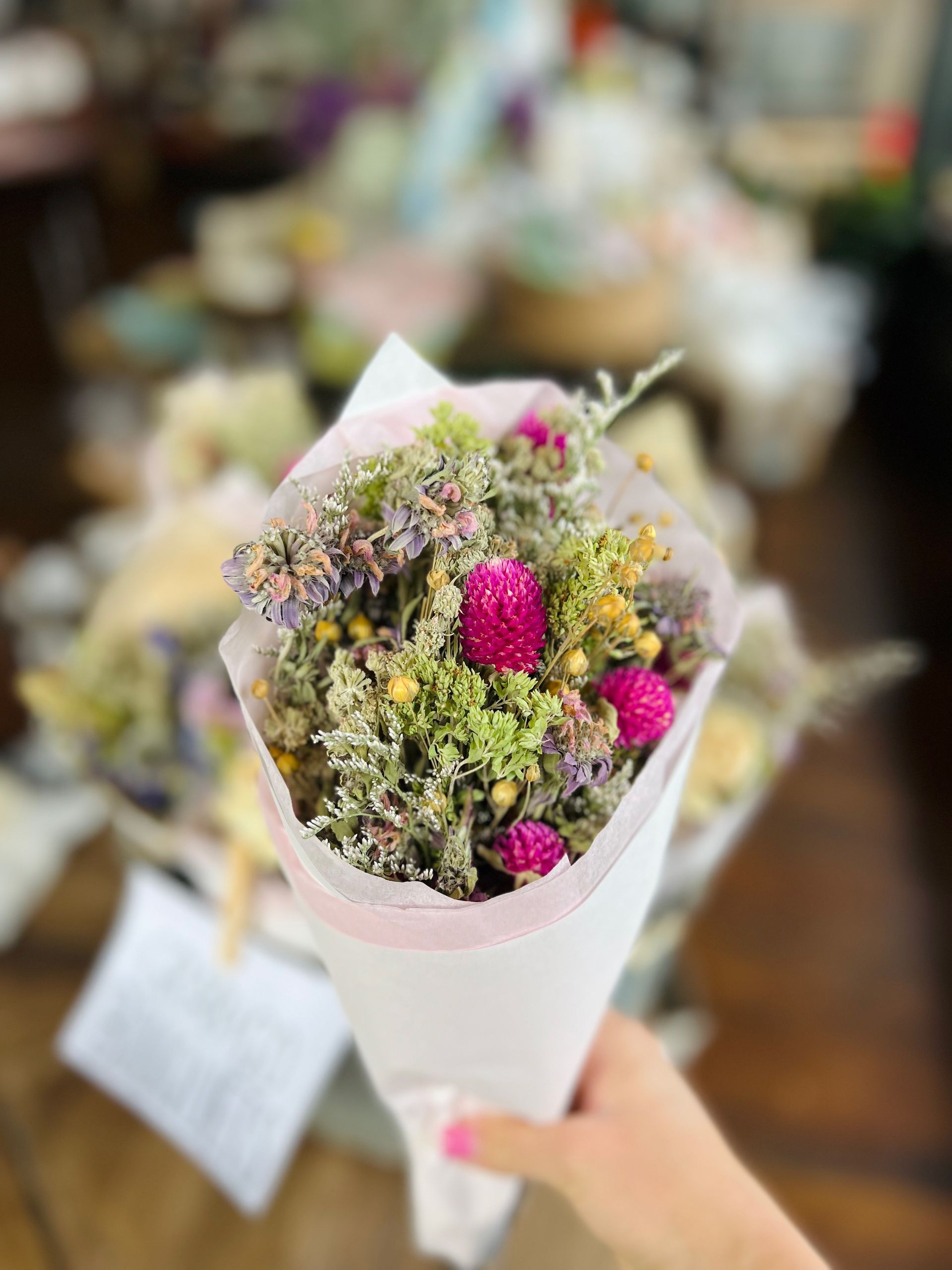 a person is holding a bouquet of dried flowers in a cone .