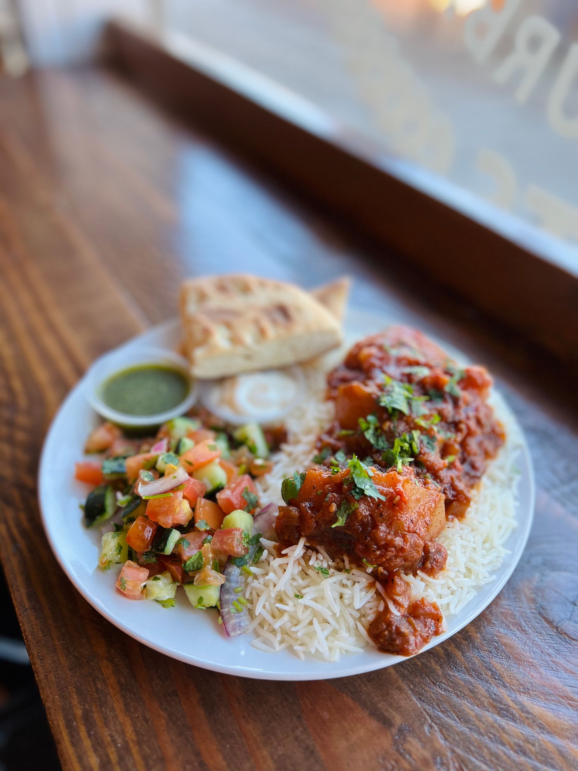 a plate of food with rice and vegetables on a wooden table .