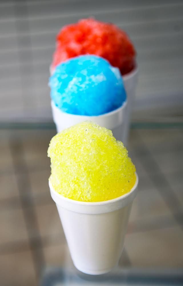 three cups of shaved ice are sitting on a glass table .