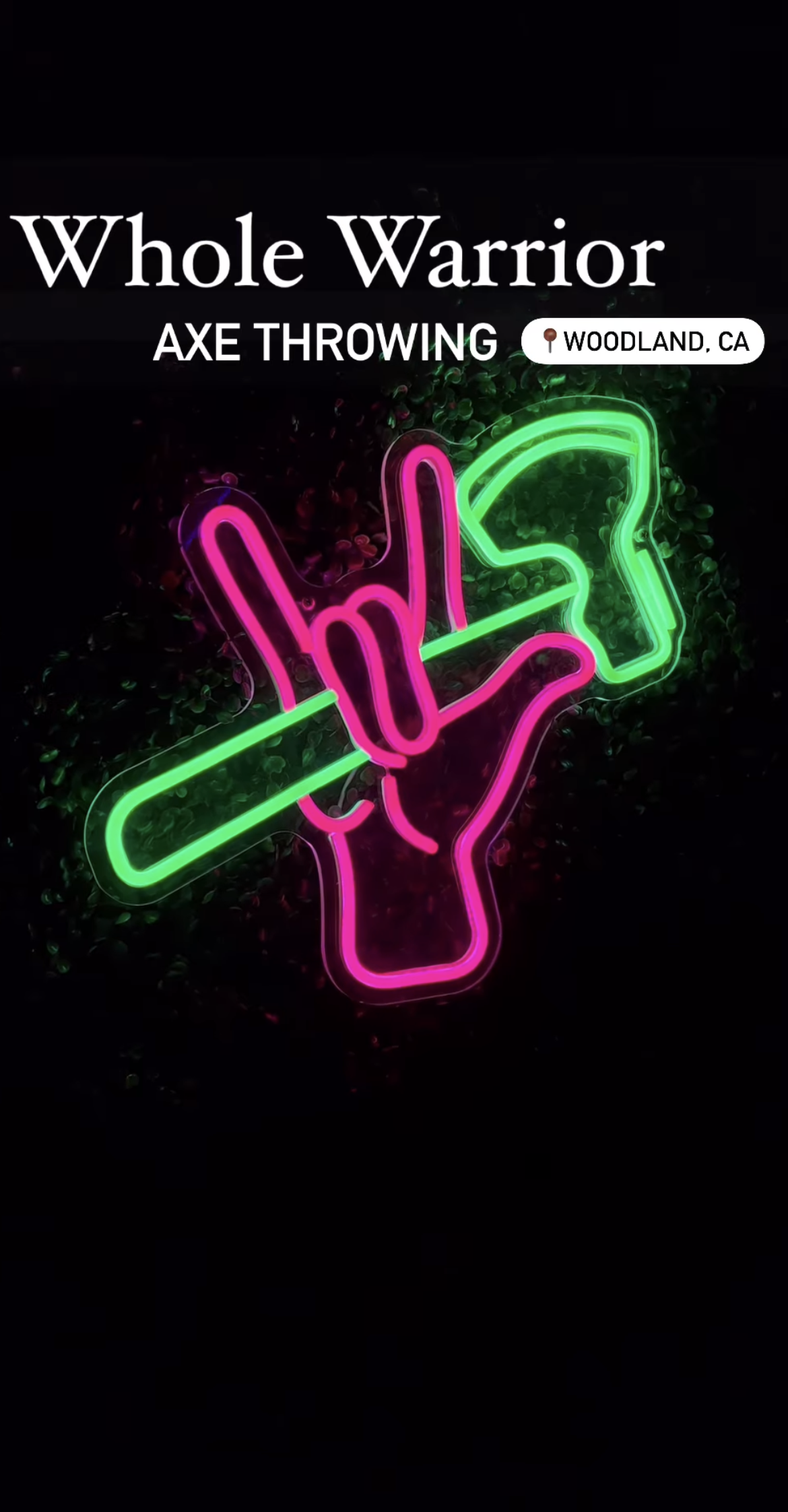 a neon sign of a hand holding a hammer on a black background .