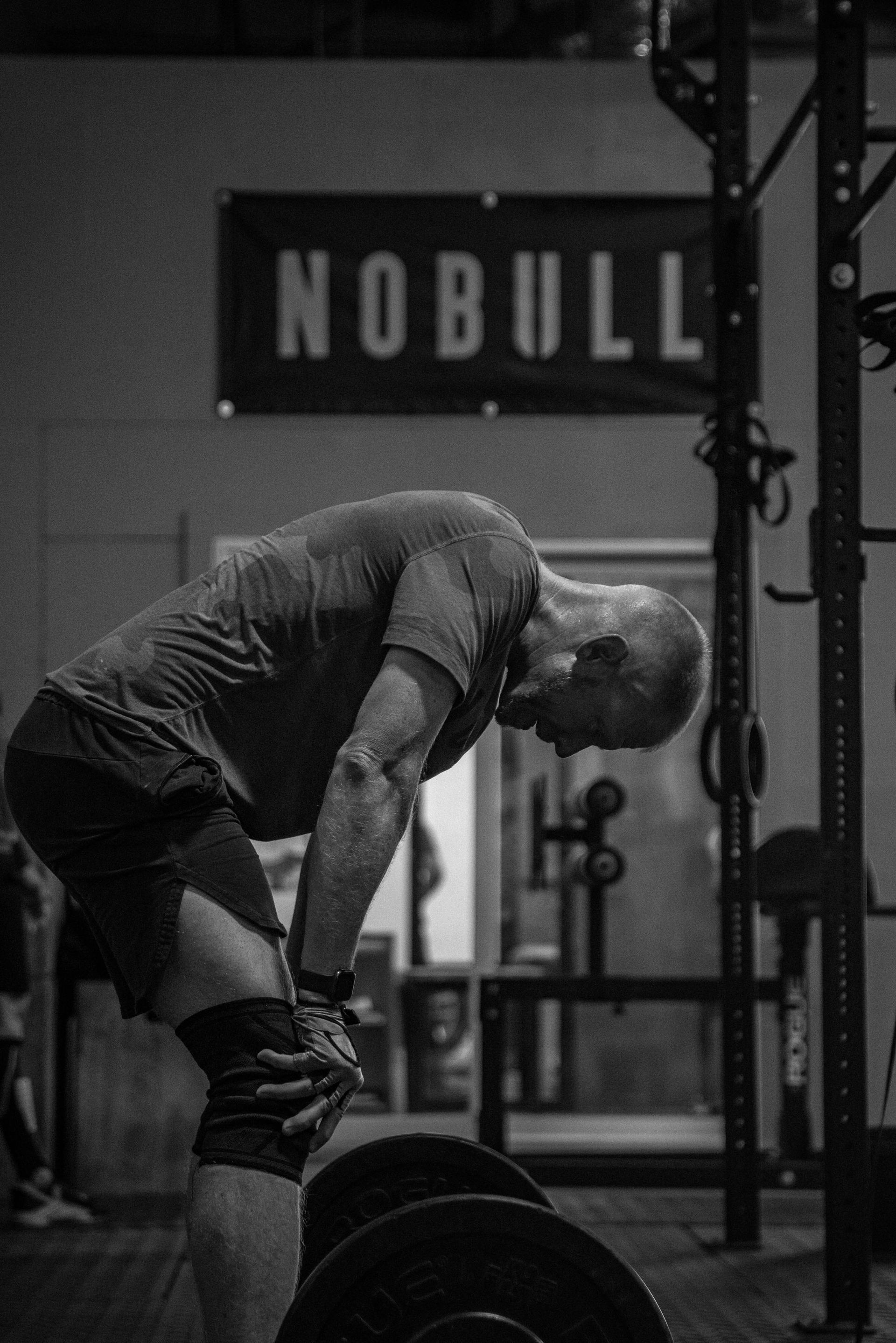 a man is lifting a barbell in a gym in a black and white photo .