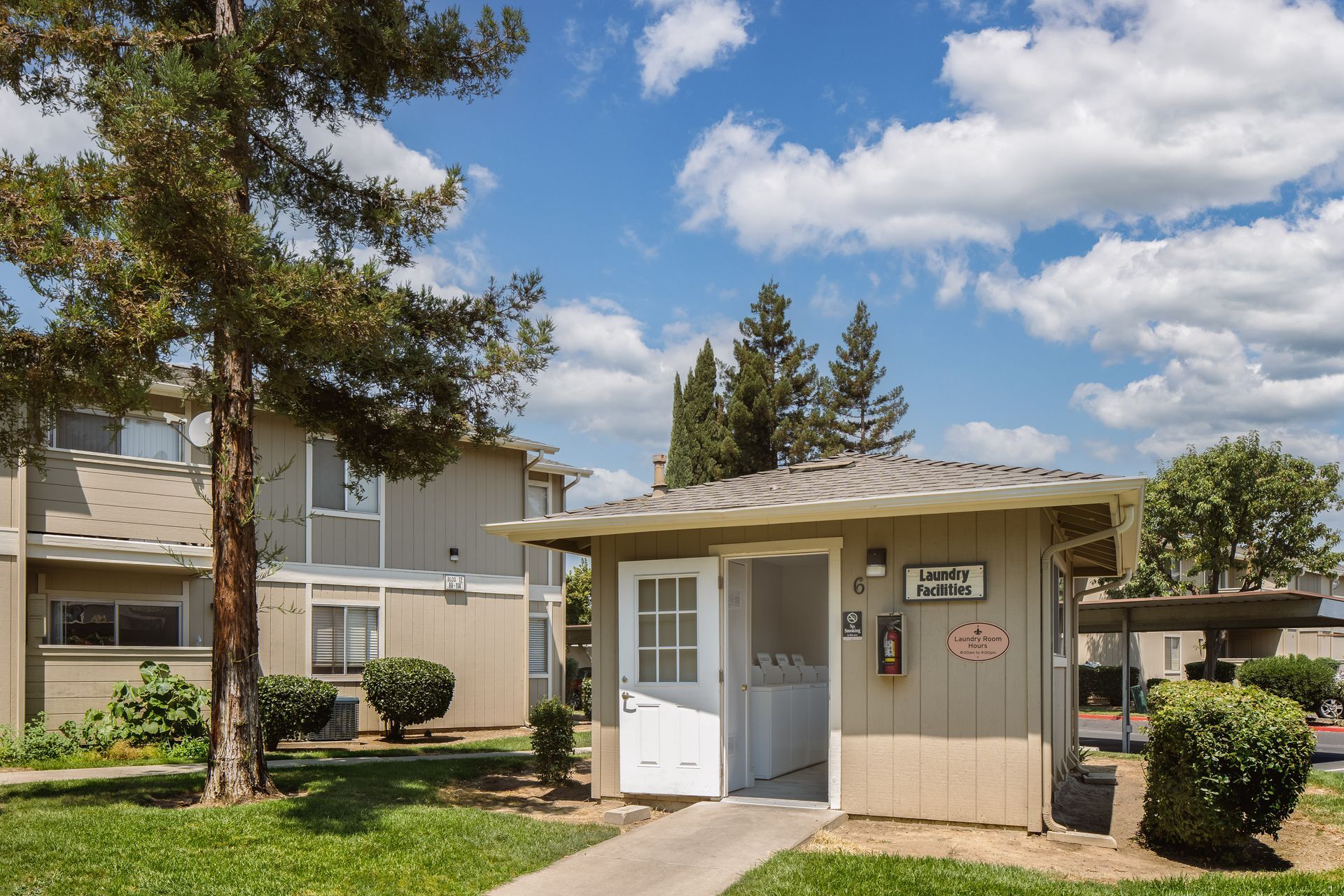 Living room with a light wooden round coffee table, gray couch, and sheer curtains.
