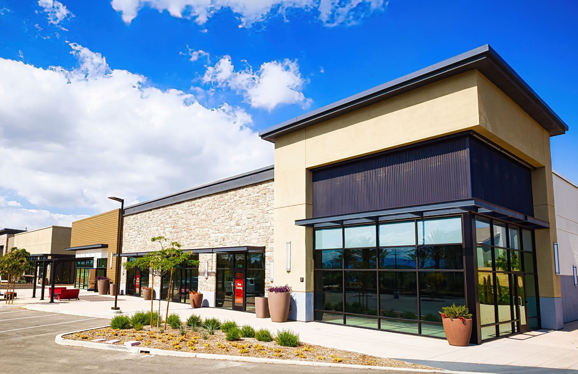 Modern retail building on a sunny day with blue sky and light-colored walls.