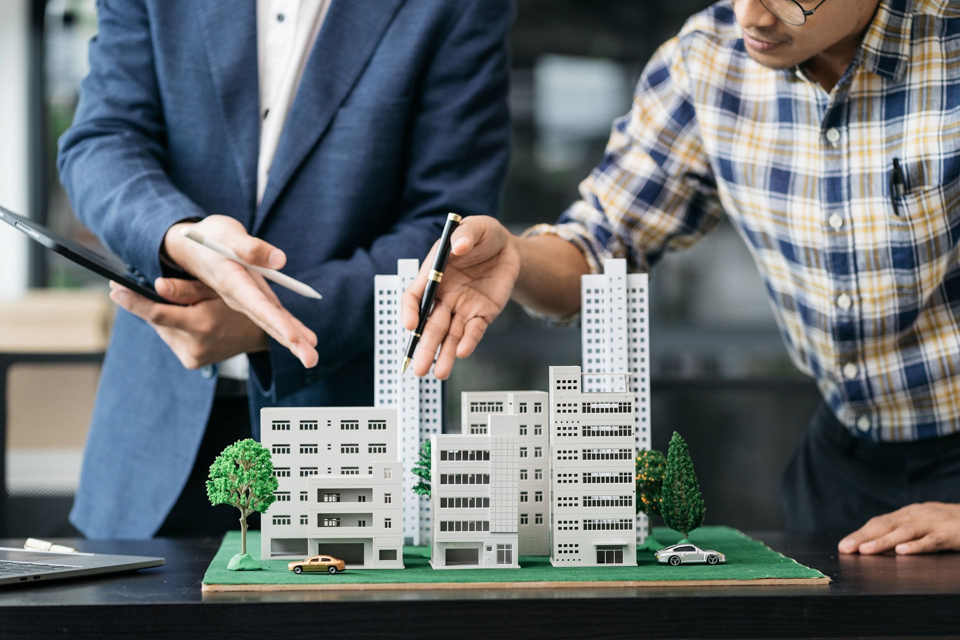 Two people examining a building model, one pointing, discussing architecture plans.
