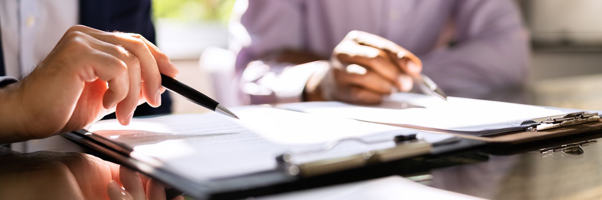 A person is holding a pen over a clipboard.