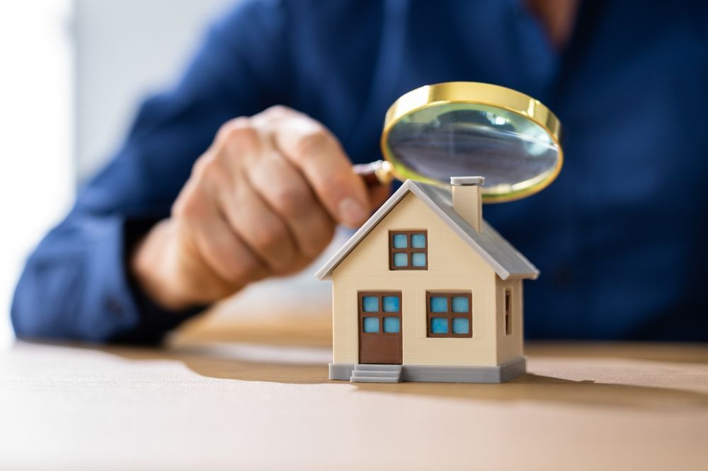 A person is looking at a model house with a magnifying glass.