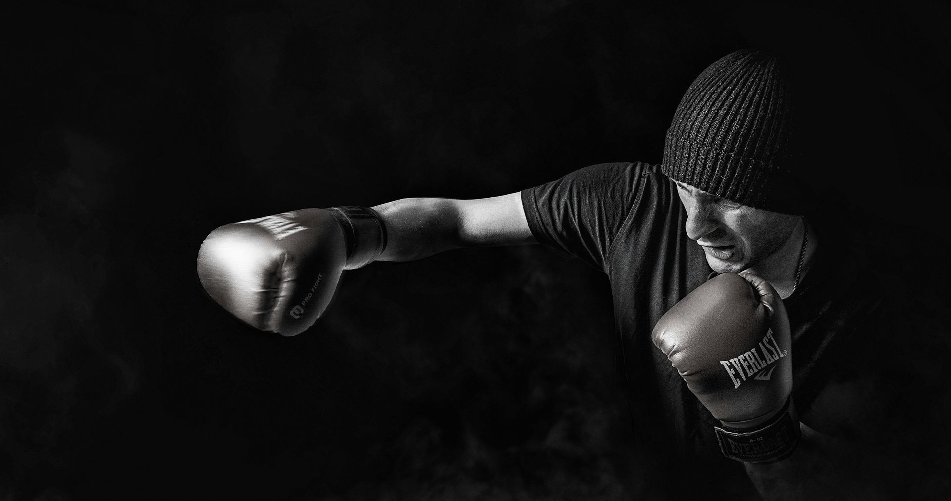 A black and white photo of a man wearing boxing gloves.