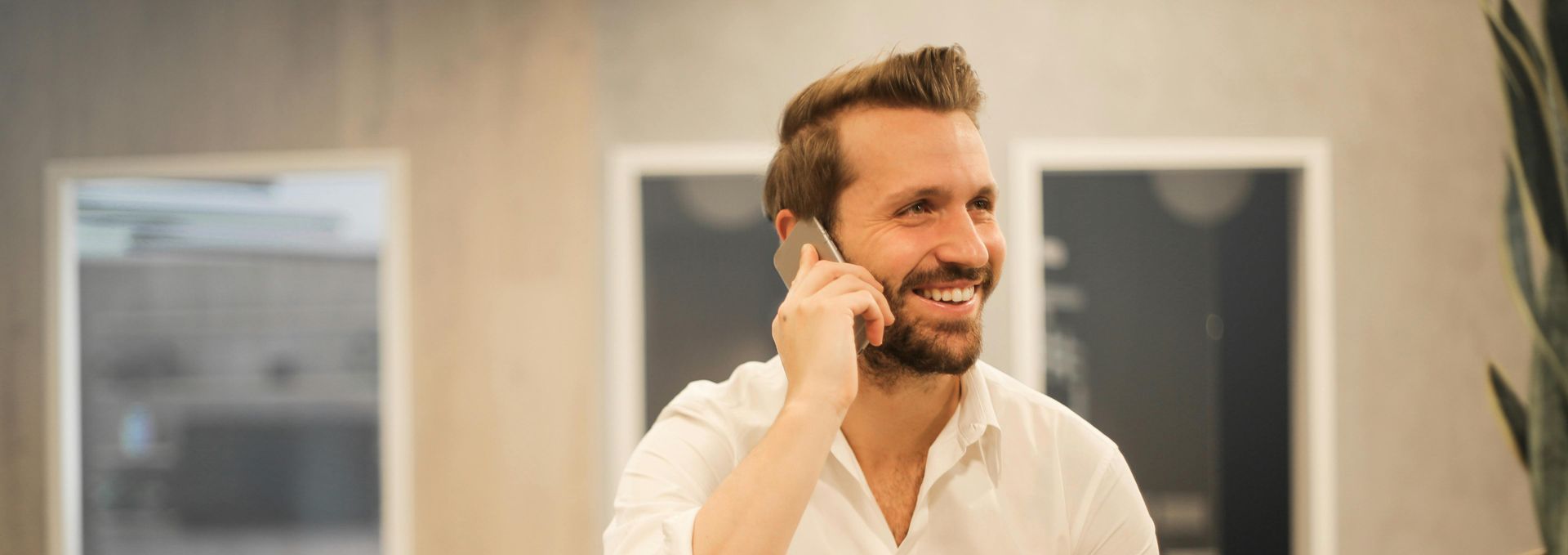 A man is smiling while talking on a cell phone.