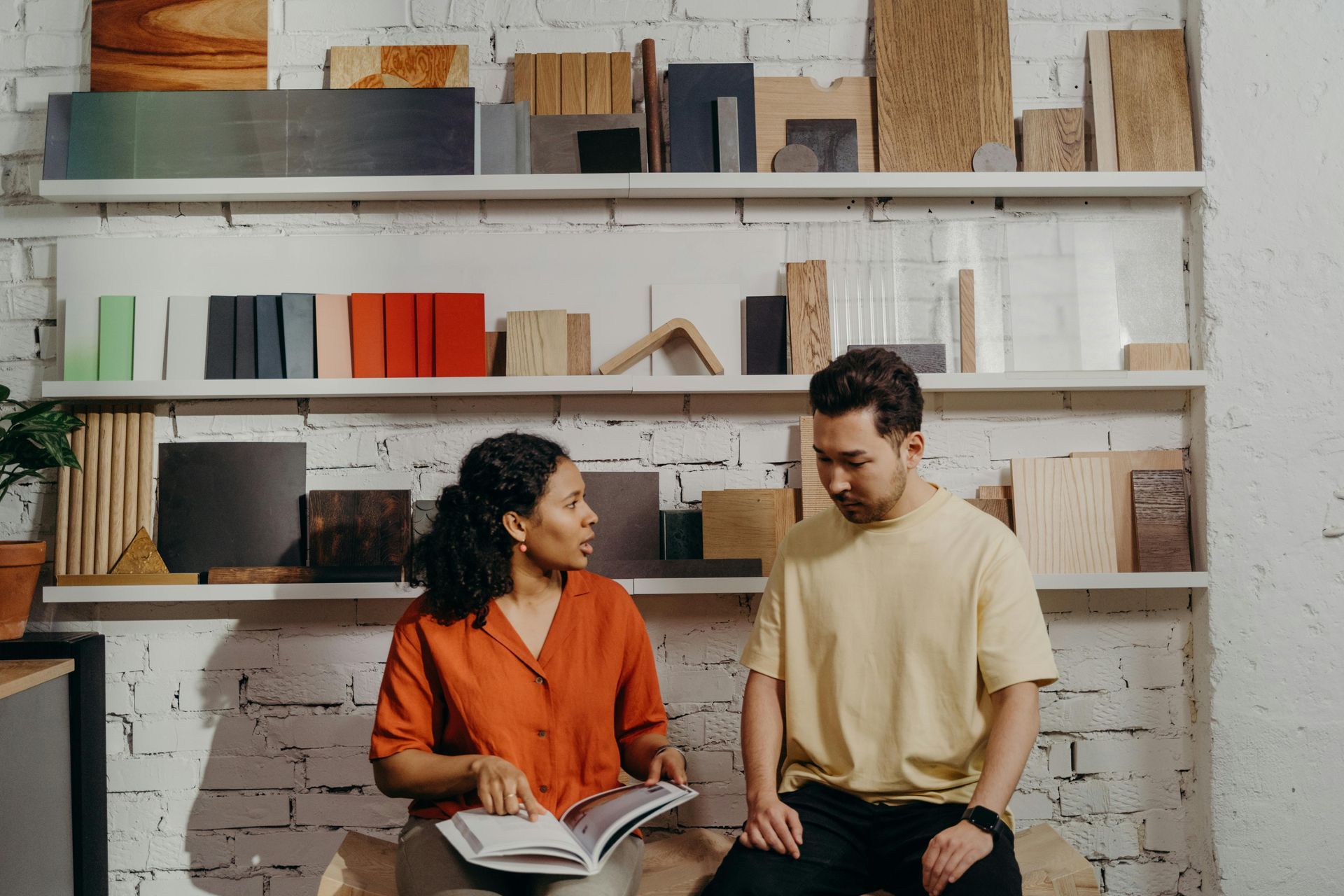 A man and a woman are sitting at a table looking at a book.