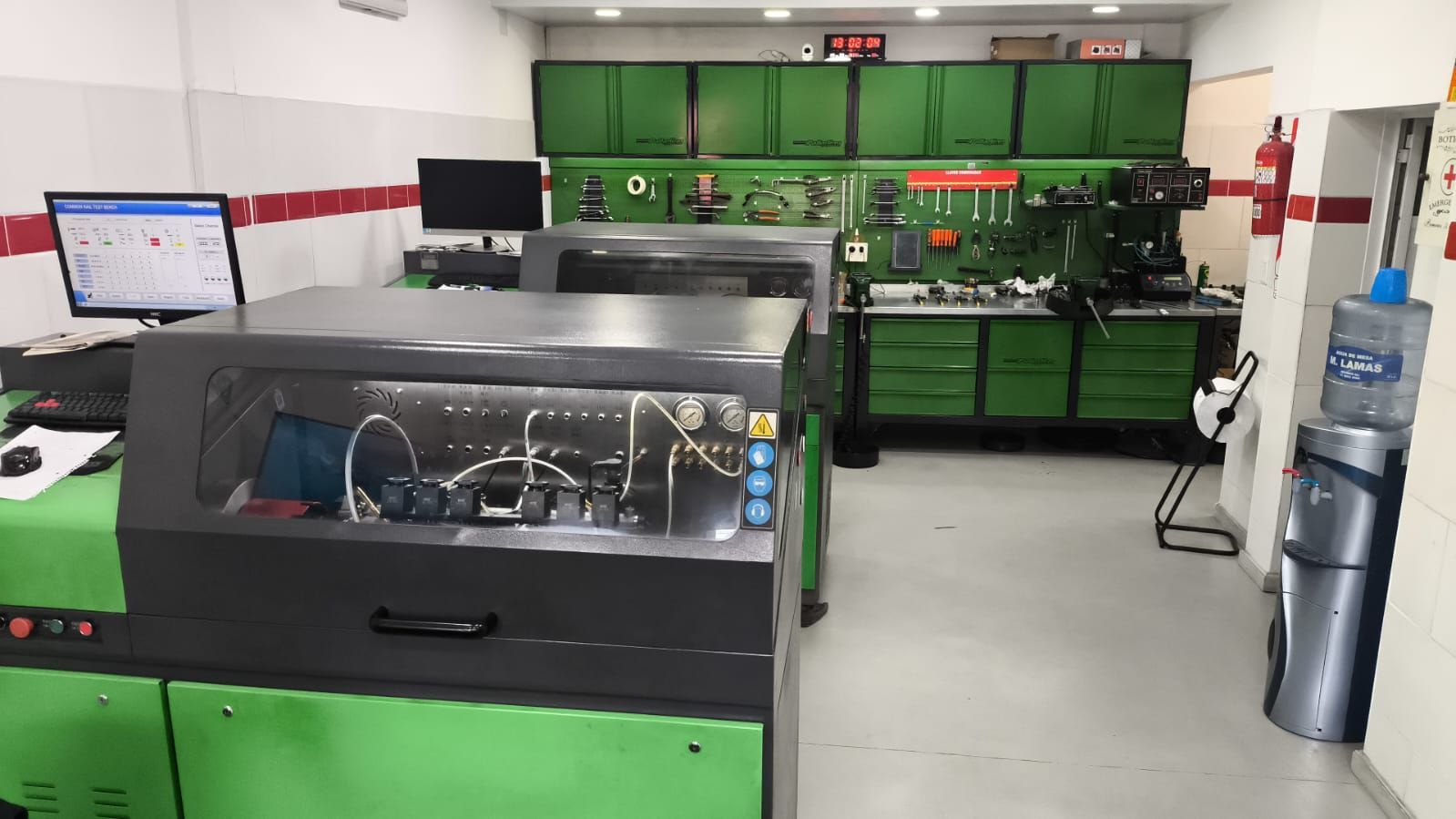 Un taller de reparación de motores diésel con equipo de diagnóstico, armarios verdes y herramientas. 