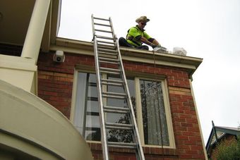 guy on roof cleaning gutters