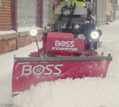 Red Boss Snowrator clearing snow on a street; white snow is piled in front of the plow.