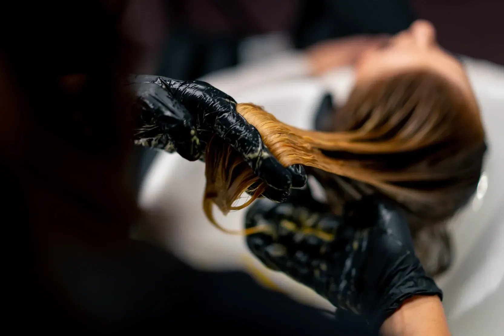 Une femme se fait teindre les cheveux par un coiffeur dans un salon.