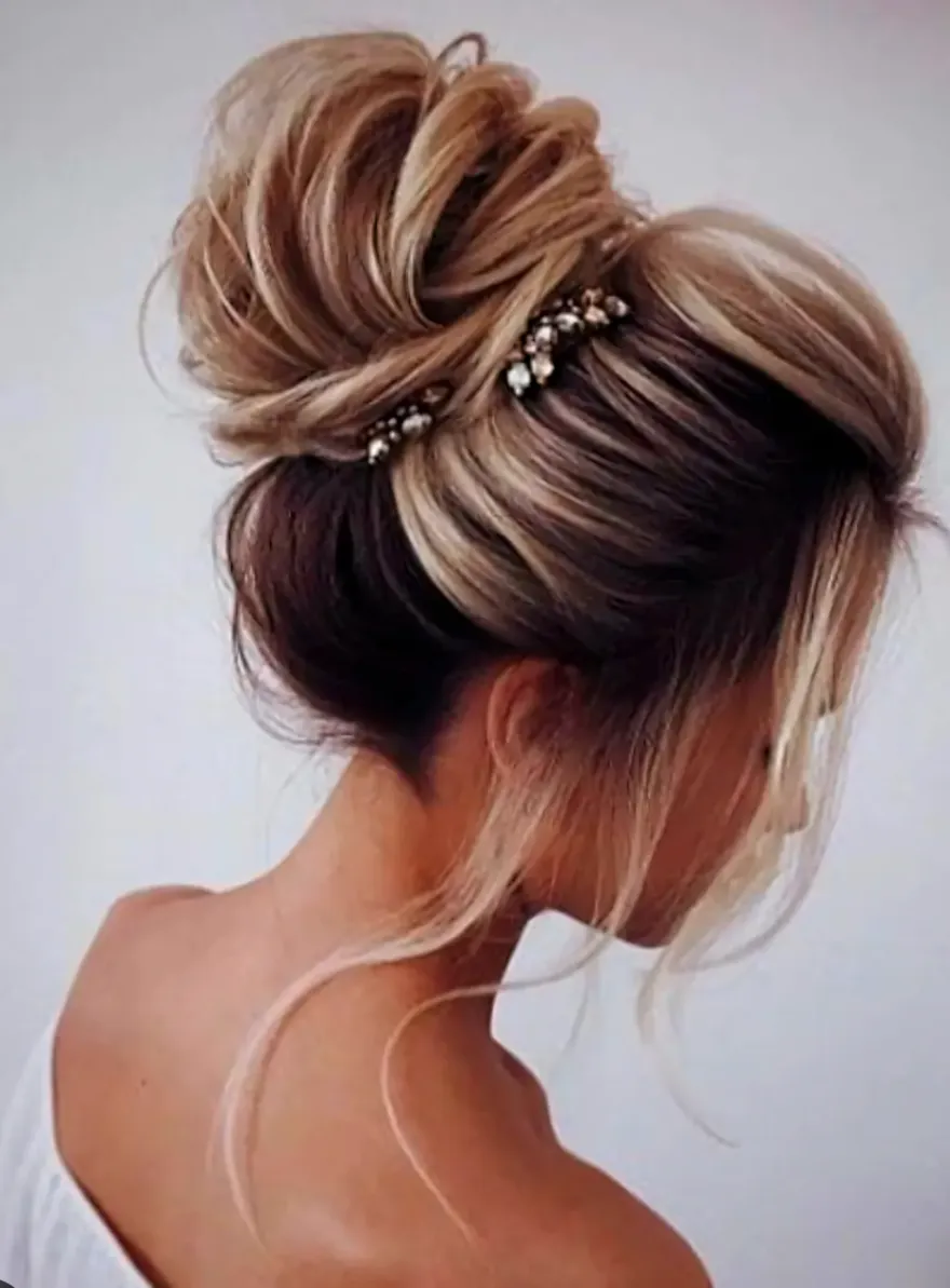 Une femme porte ses cheveux en chignon désordonné avec des perles.