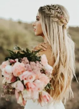 Une femme en robe de mariée tient un bouquet de fleurs roses.