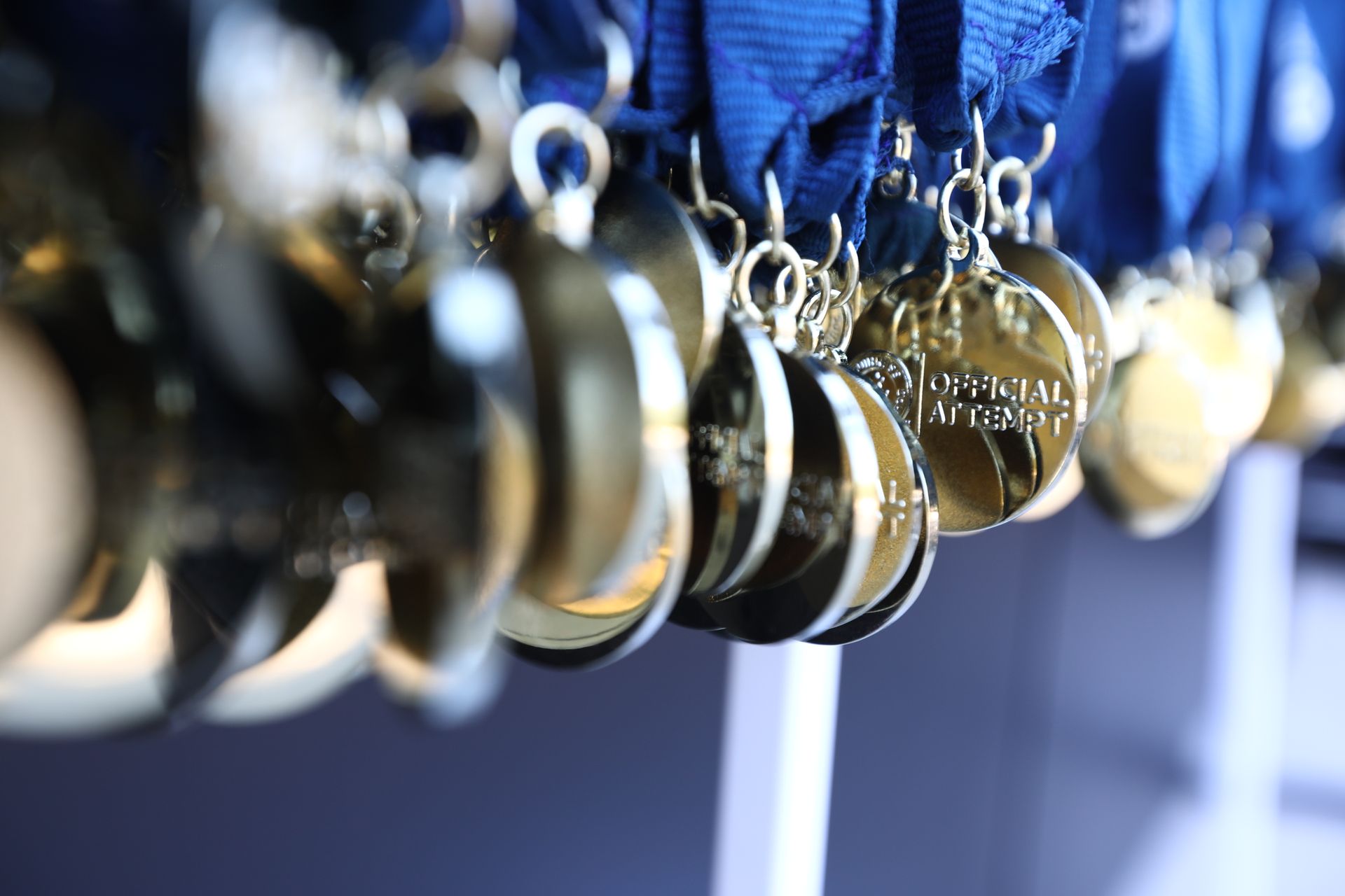 Gold medals hanging on blue ribbons, close-up, blurry background.
