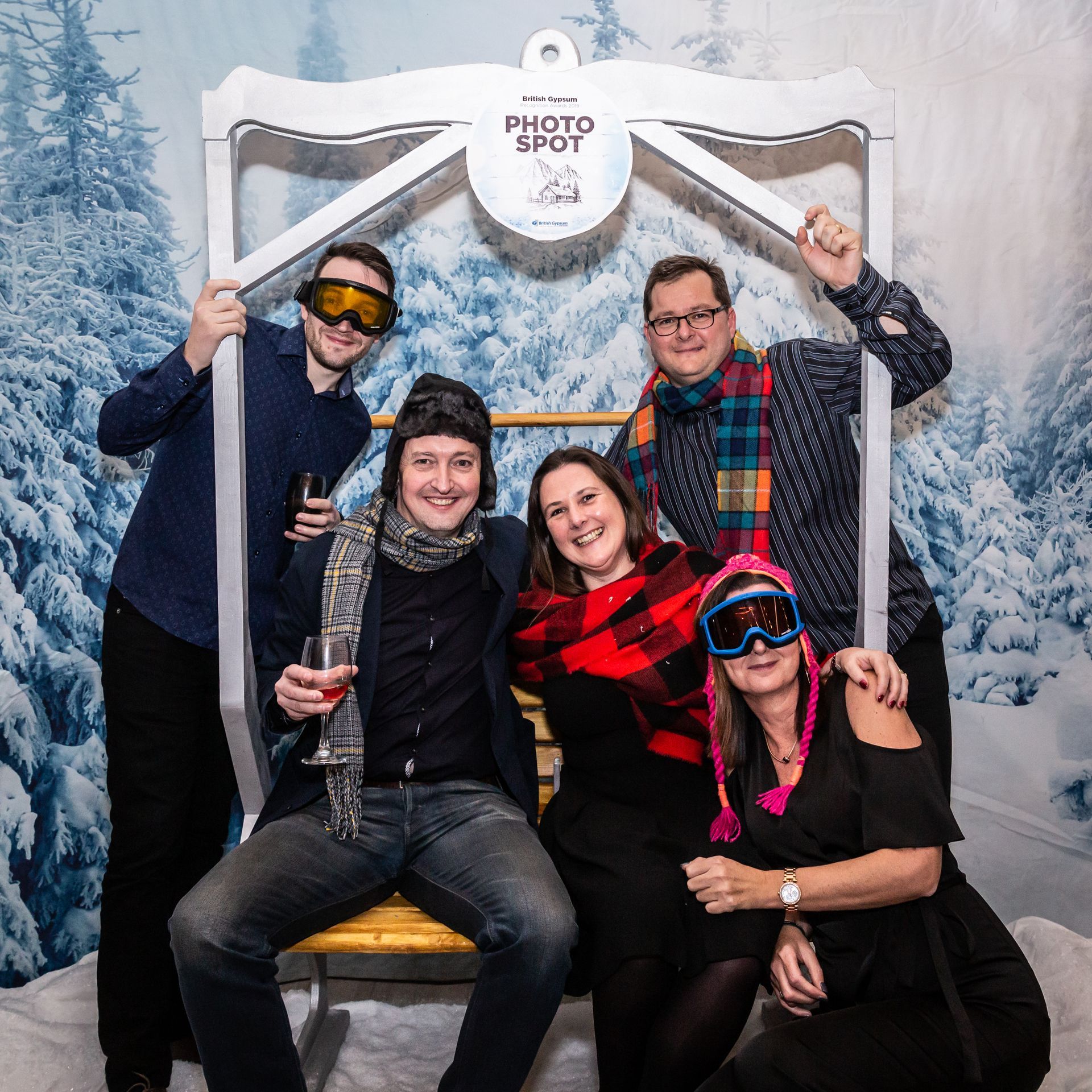 Group of people in winter attire posing at a photo spot with a snowy background.
