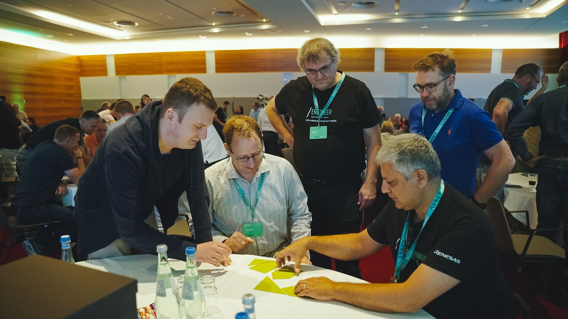 A group of people at a conference work together, looking at yellow cards on a table.
