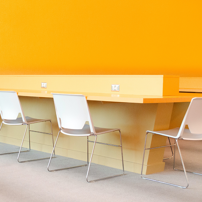 A row of white chairs sitting in front of an orange wall