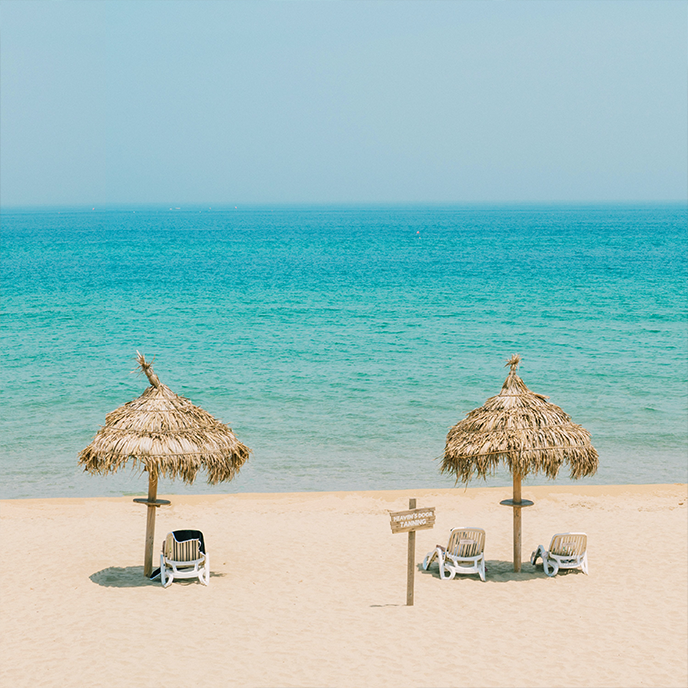 Two umbrellas and chairs on a beach with a sign that says no swimming