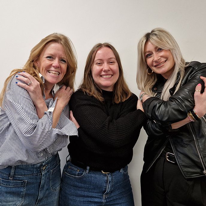 Three women are posing for a picture and smiling for the camera