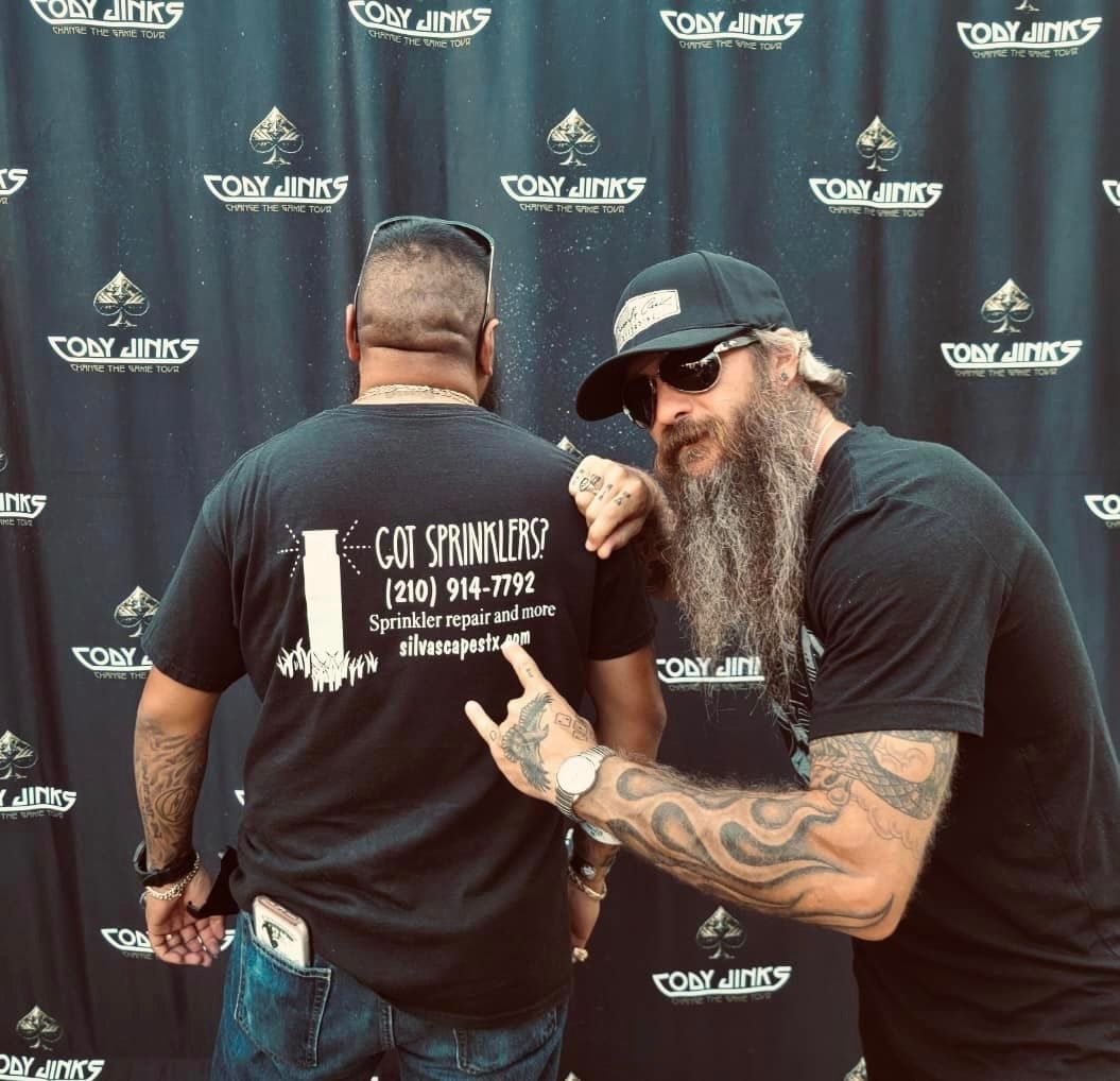 Two men are posing for a picture and one has a cat stamping shirt on