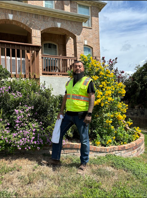 A man in a yellow vest is standing in front of a house.