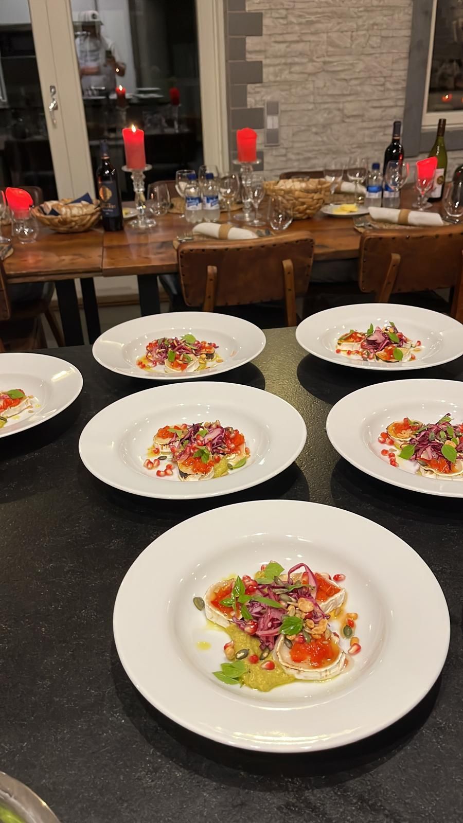 Pöydällä tarjoiltuja alkupaloja. Jokaisella annoksella on valkoinen pohja, jonka päällä on värikkäitä aineksia. Ruokapöytä taustalla.