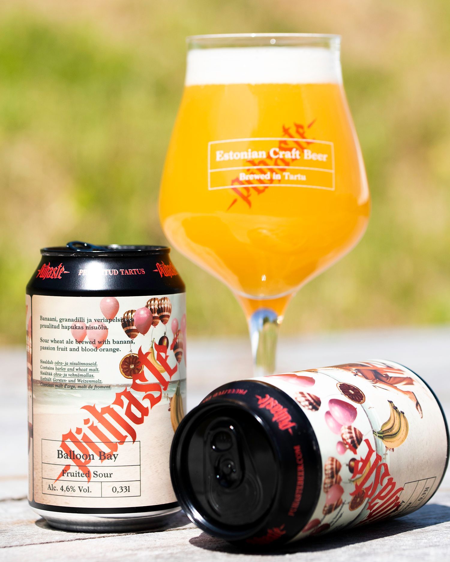 Kaksi oluttölkkiä ja lasillinen olutta, sumennettu ulkotausta. Tölkkien etiketeissä on hedelmiä, olut on vaaleanoranssia.