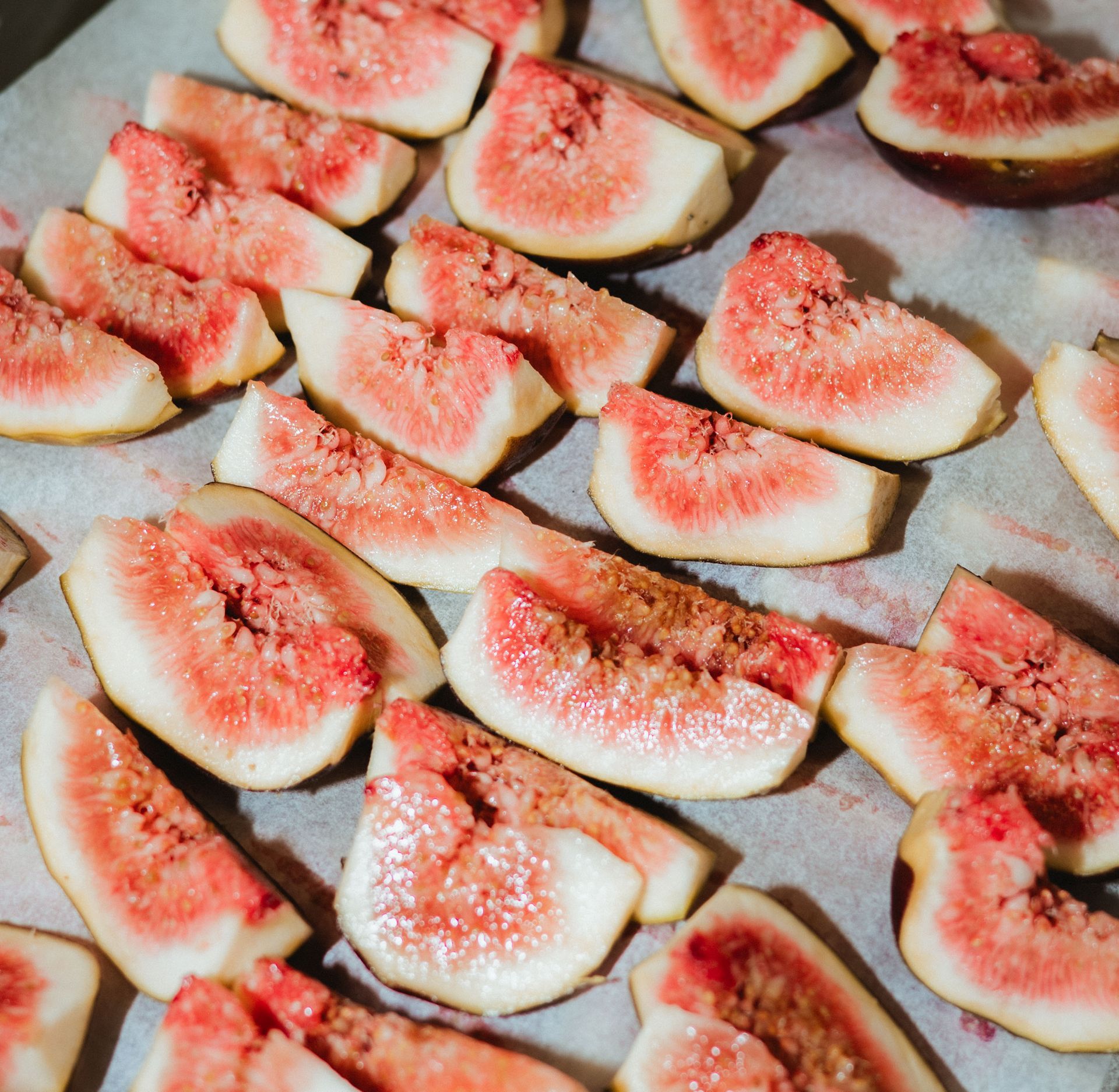 Viipaloidut tuoreet viikunat, vaaleanpunainen hedelmäliha, aseteltuna pergamenttipaperille.