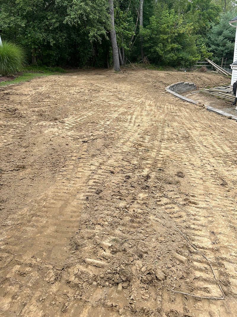 A large pile of dirt in a yard with trees in the background.