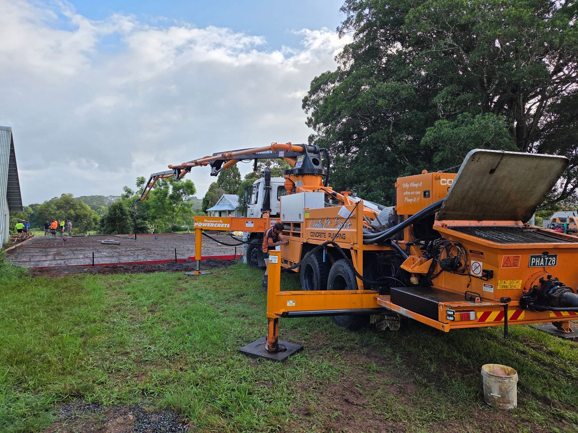 Orange concrete pump truck at a construction site, pouring concrete. Overcast day.