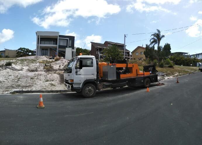 A White Truck With Orange Machinery Parked on a Road — Coota & Son's Concrete Pumping In Byron Bay, NSW