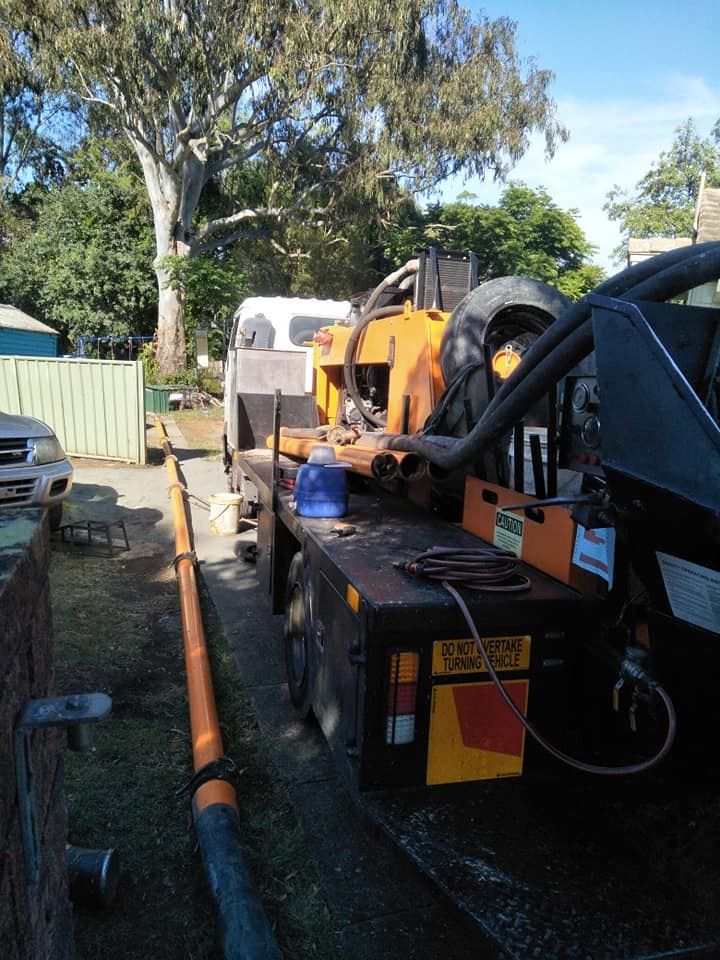 Truck With Orange Equipment and Long Pipe on a Residential Street — Coota & Son's Concrete Pumping In Casino, NSW
