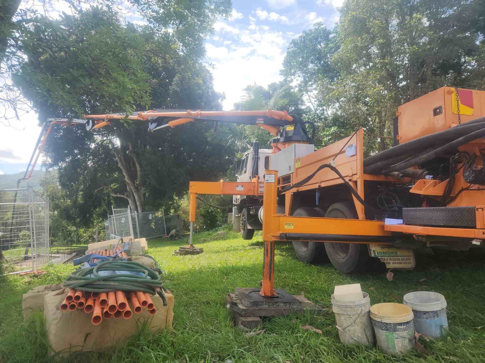 Orange Drilling Rig on Grass, Boom Extended — Coota & Son's Concrete Pumping In Evans Head, NSW