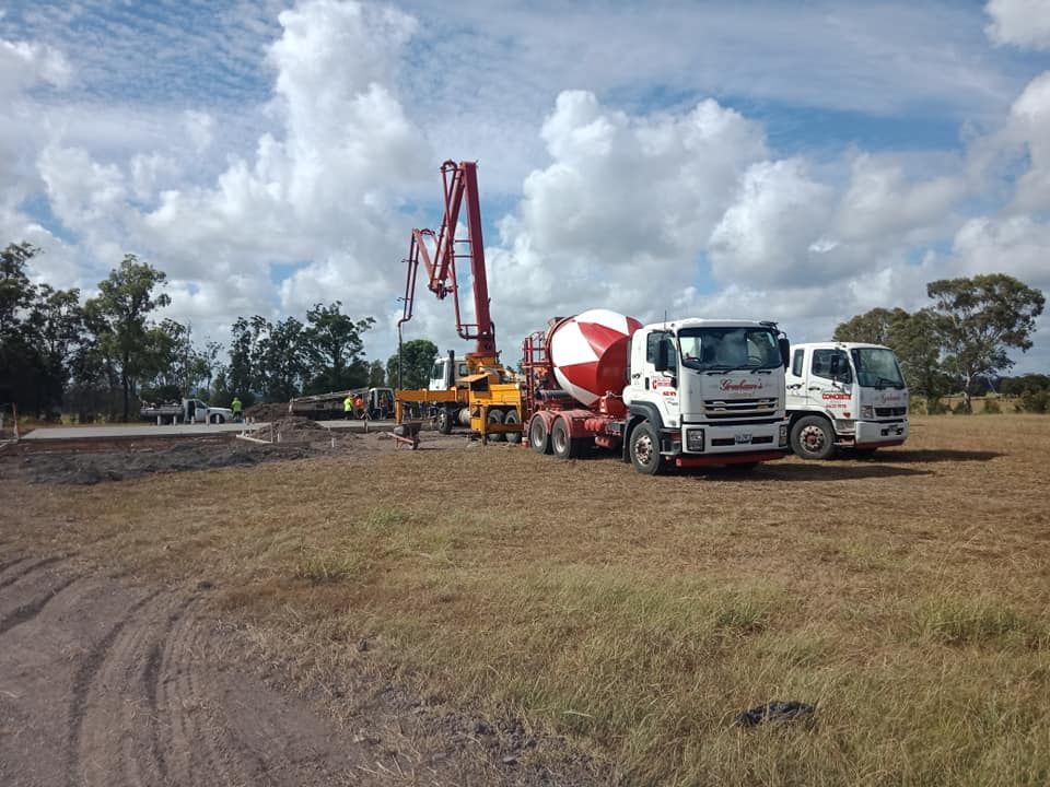 Concrete Trucks and Pump on a Construction Site Under a Partly Cloudy Sky — Coota & Son's Concrete Pumping In Lismore, NSW