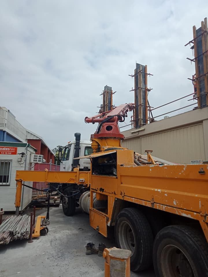 Orange Concrete Pump Truck With a White Truck Behind It — Coota & Son's Concrete Pumping In Kyogle, NSW