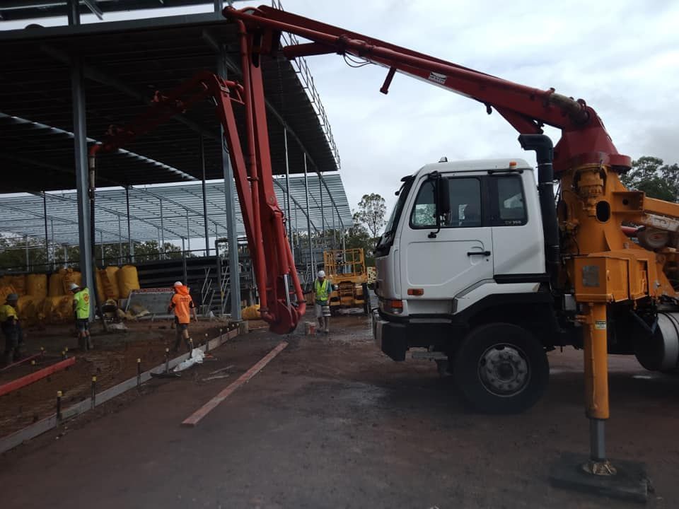 A Red Concrete Pump Truck is Positioned Near Construction Site — Coota & Son's Concrete Pumping In South Gundurimba, NSW