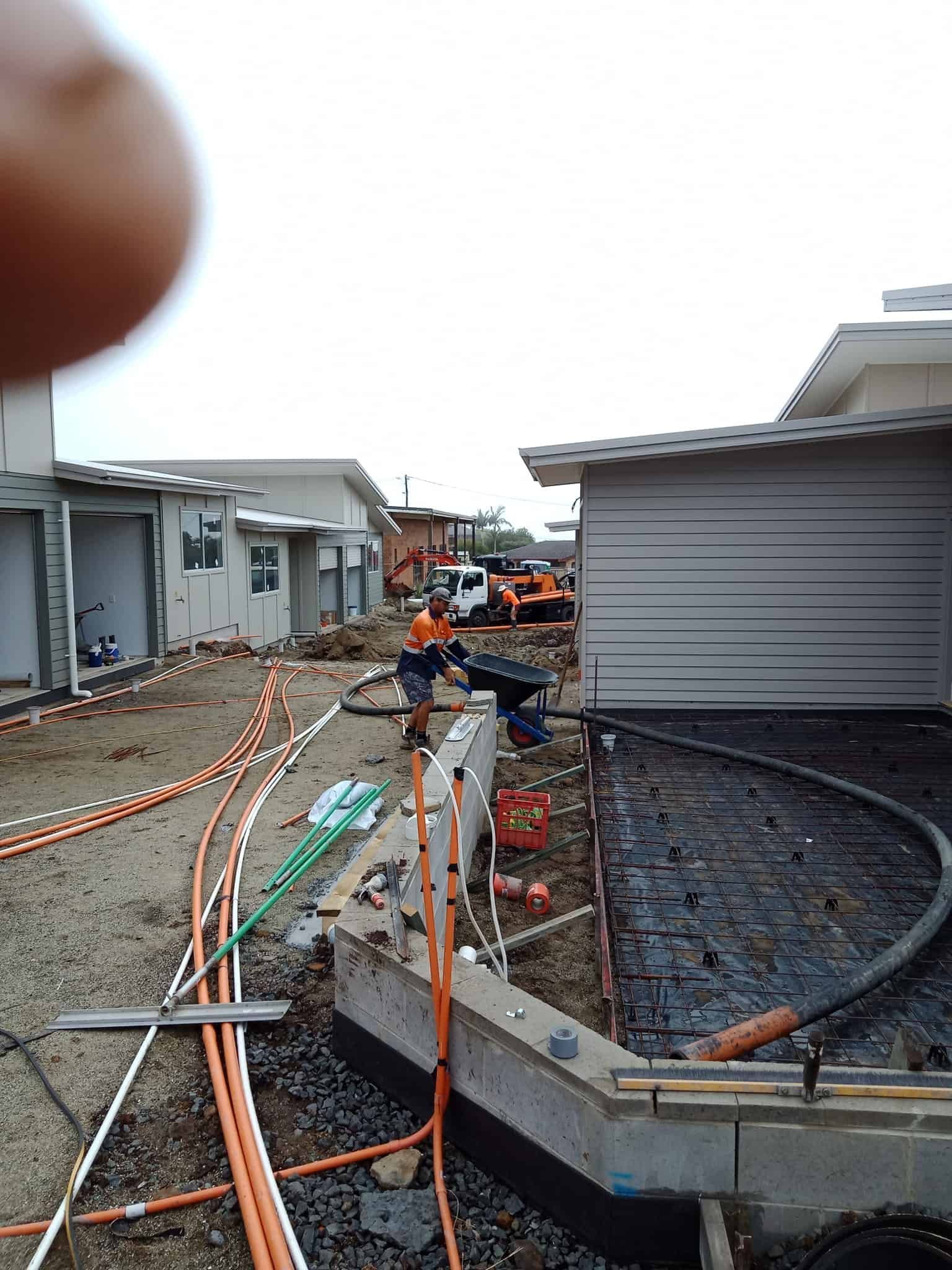 Construction Site With Workers Laying Pipes; Buildings in Background — Coota & Son's Concrete Pumping In Tenterfield, NSW