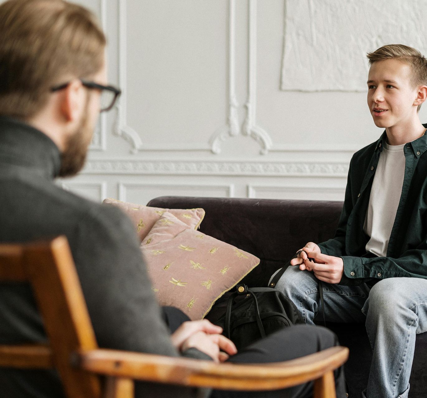 Two men are sitting on a couch having a conversation.