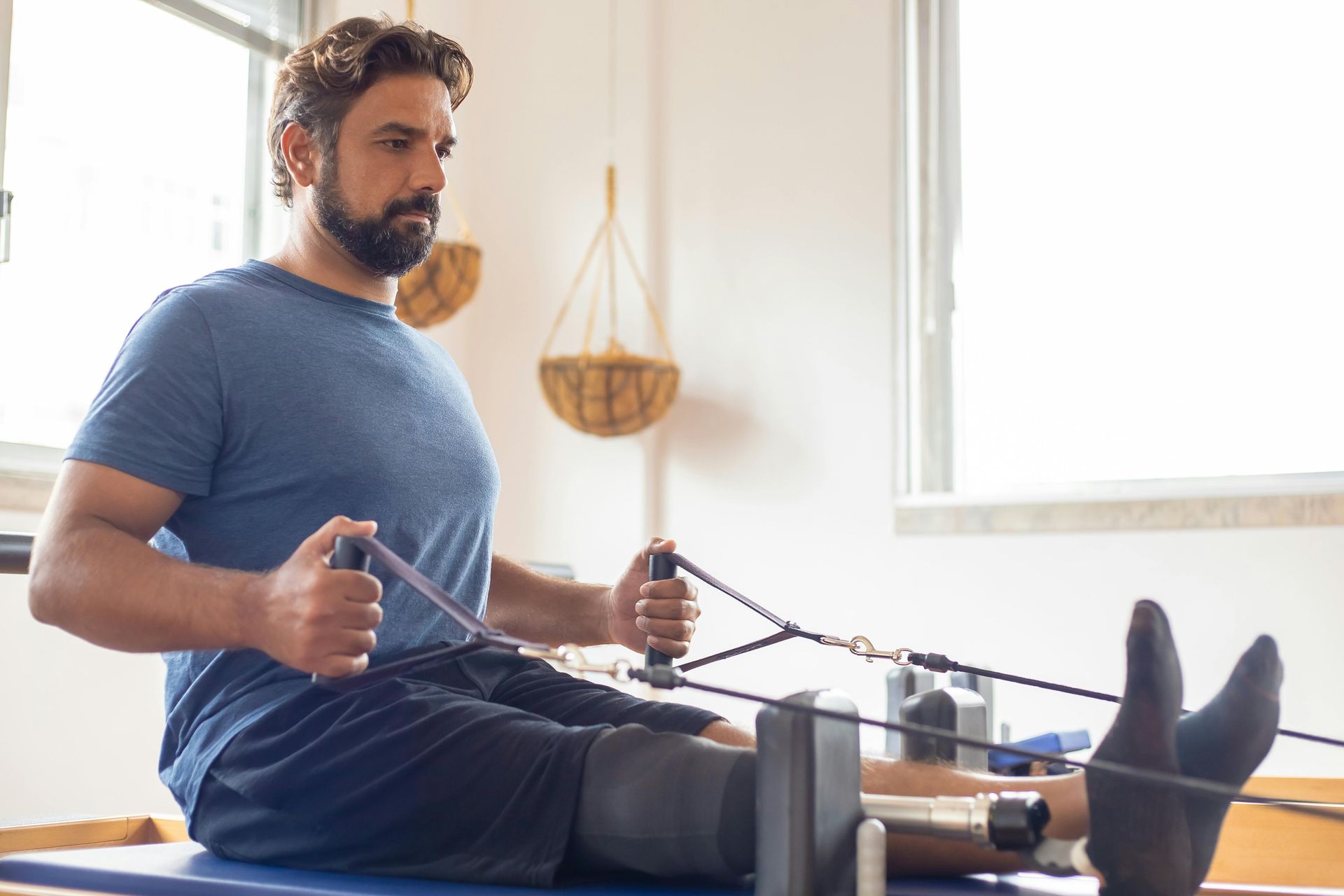 A man is sitting on a pilates machine in a gym.