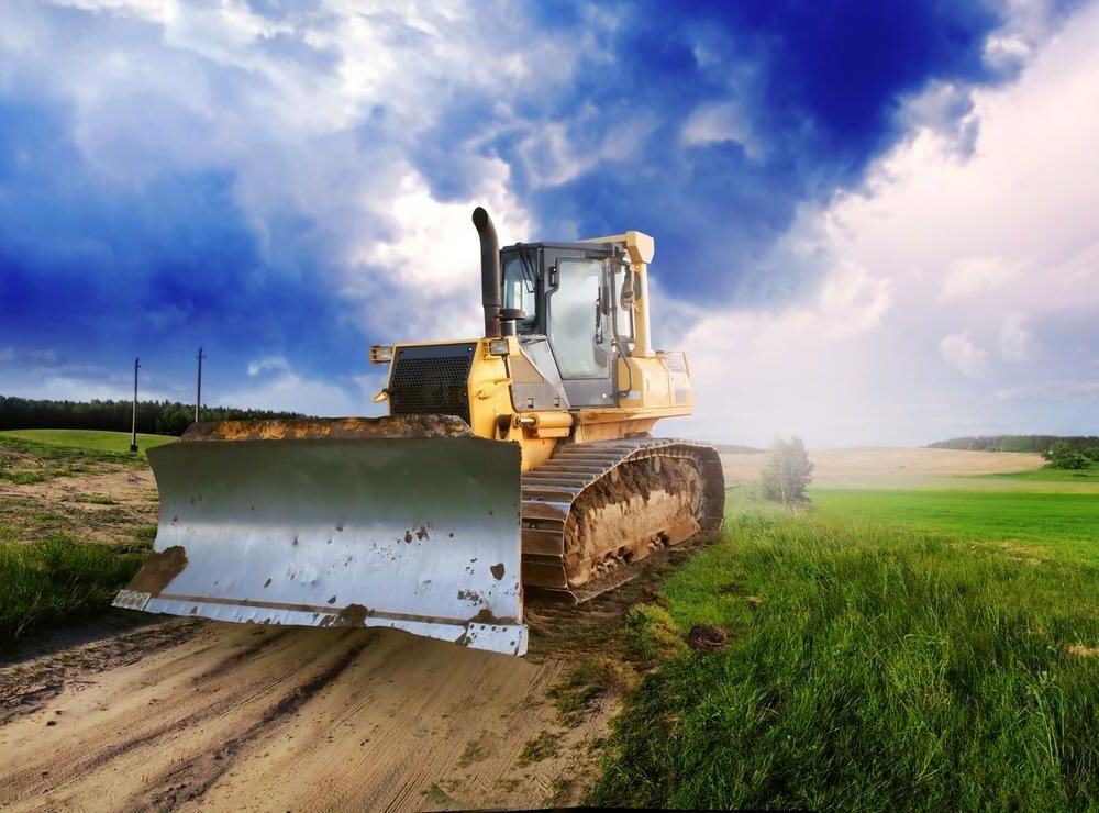 A Bulldozer Is Driving Down A Dirt Road In A Field — JBS Mobile In Bangalow, NSW