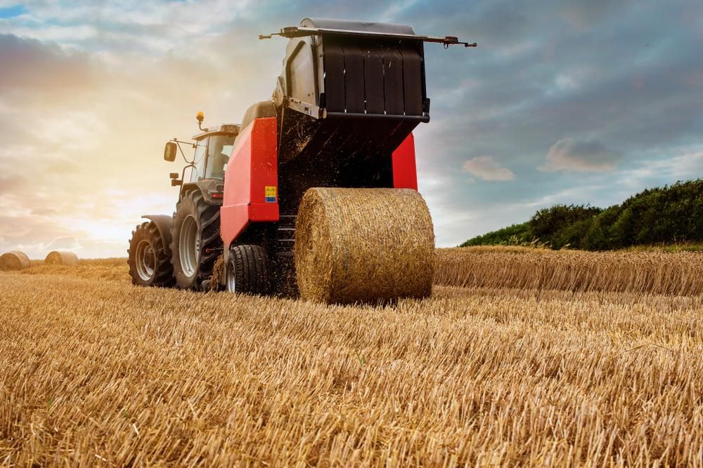 A Tractor Is Baling Hay In A Field — JBS Mobile In Richmond Hill, NSW