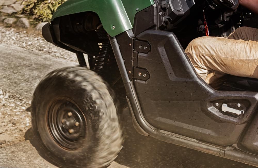 A Person Is Driving A Green Atv On A Dirt Road — JBS Mobile In Richmond Hill, NSW