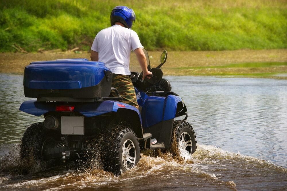 A Man Is Riding A Blue Atv Through The Water — JBS Mobile In Lismore, NSW