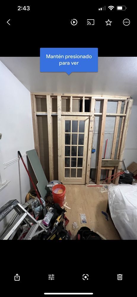 Interior framing with a door installed, surrounded by construction materials in a room.